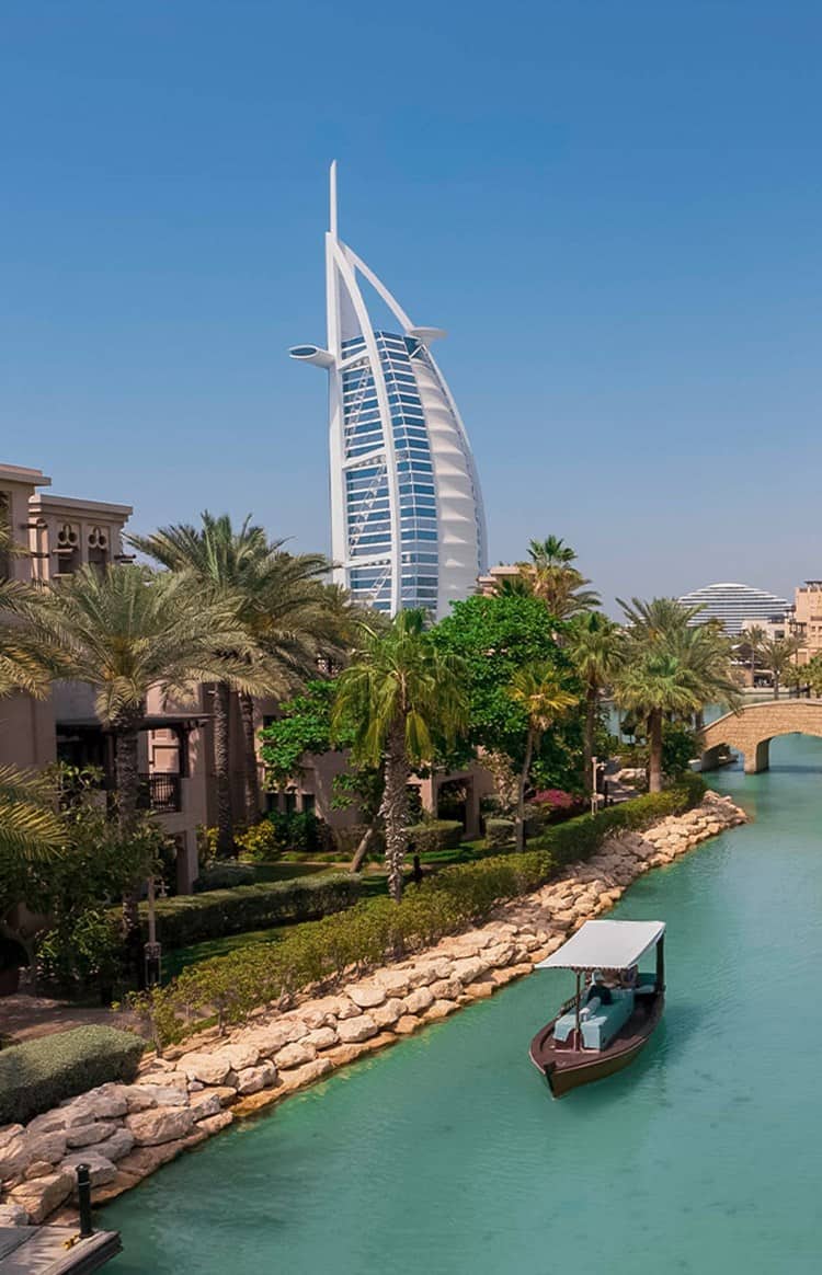 A traditional Emirati boat on a waterway next to Madinat Jumeirah with Burj Al Arab in the background.