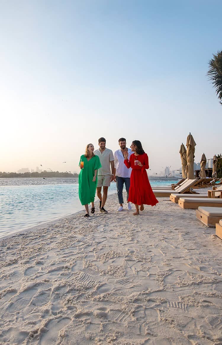 Group of four people walking along the beach