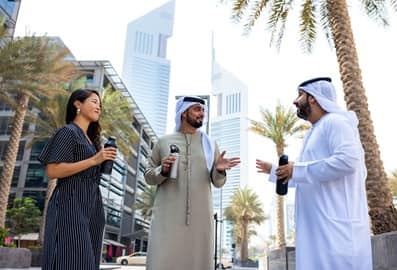 People carrying reusable water bottles during a conversation in a public space