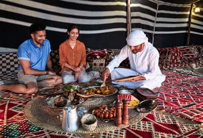 Emirati man in a bedouin tent serving traditional Emirati food to tourists