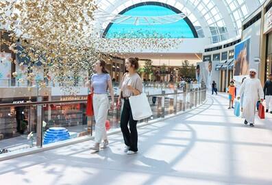 Shoppers walking through the modern interior of Dubai Hills Mall