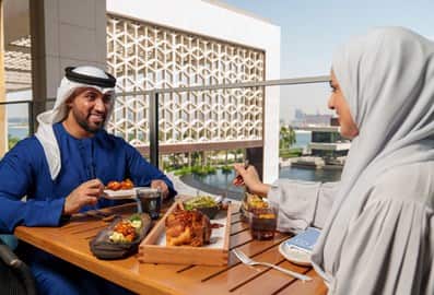 A couple enjoying outdoor fine dining at a waterfront restaurant in Dubai