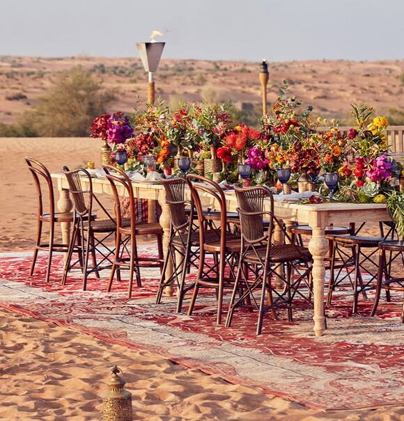 Tisch mit Stühlen und Blumen in der Wüste von Dubai