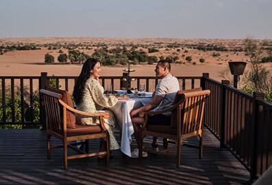 A young couple sitting on a terrace with a beautiful desert landscape in the background.