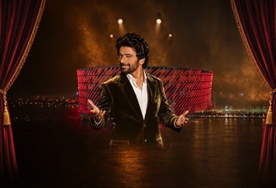 Performer in a black suit on stage during a live show