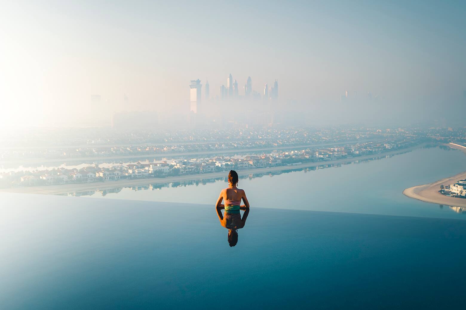 woman in swimming pool looking at the palm view 