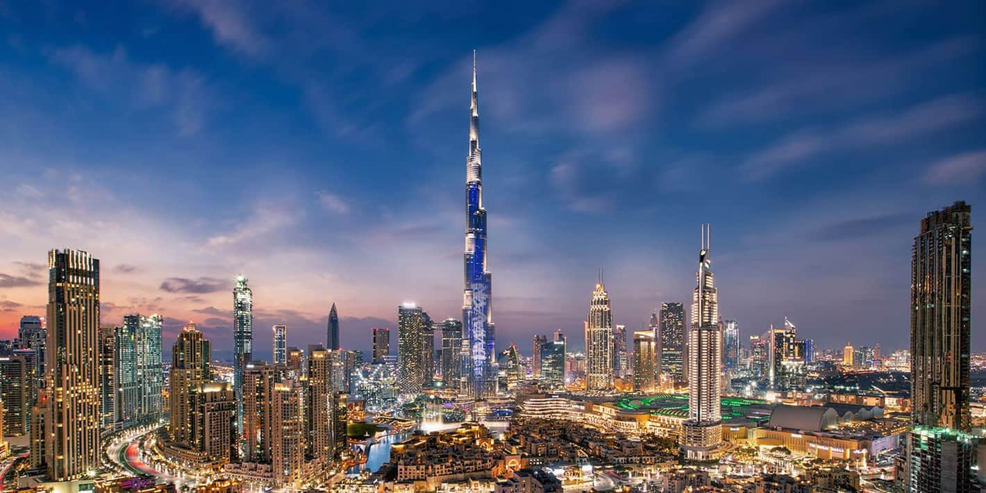 Aerial view of Dubai's majestic skyline at night with Burj Khalifa at its centre.