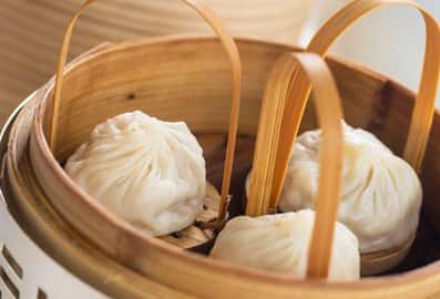 Freshly steamed dim sum dumplings served inside a traditional bamboo steamer basket at Royal China restaurant in Dubai