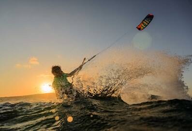 Kitesurfer riding waves at sunset