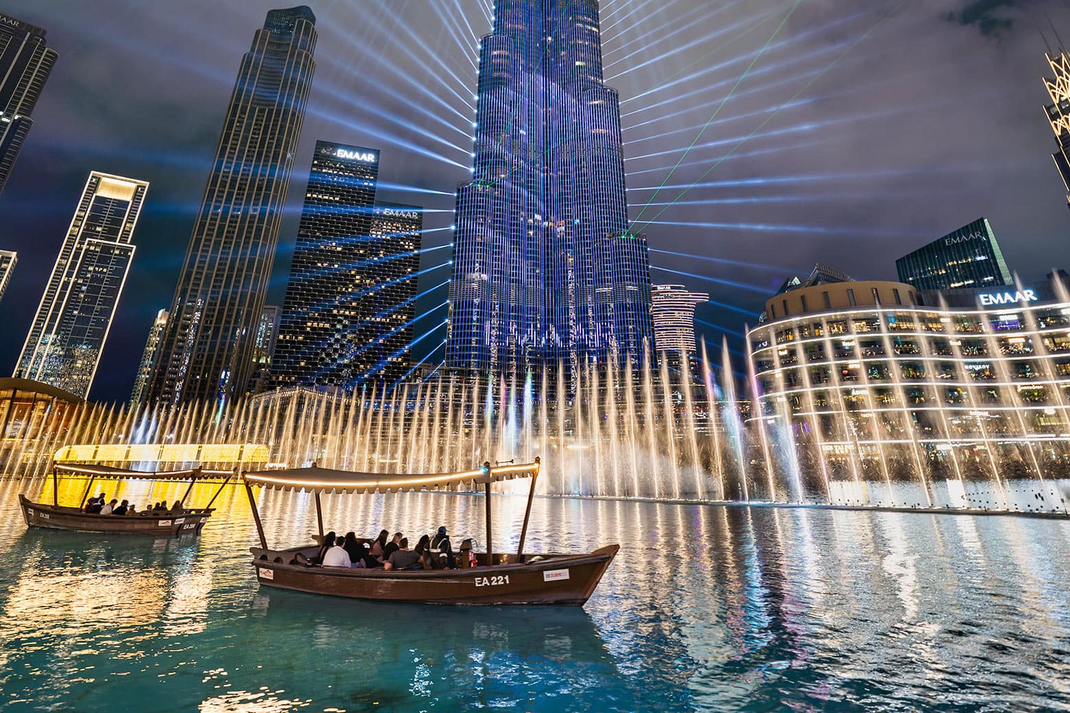 Traditional abra boats on the lake in front of the illuminated Dubai Fountain at night