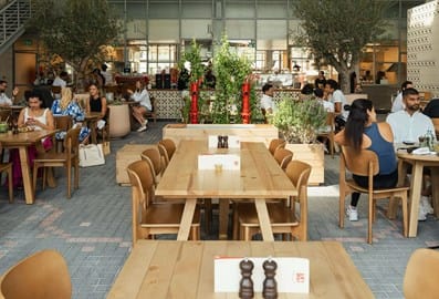 Seating area with tables and people at The Growhouse by One Life in Dubai