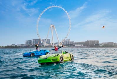 People in boats shaped like sports cars in front of Al Ain Dubai