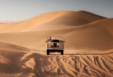 Desert safari vehicle travelling across golden sand dunes