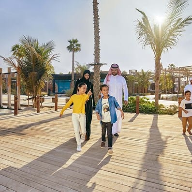 Saudi family with children walking along a wooden seaside boardwalk