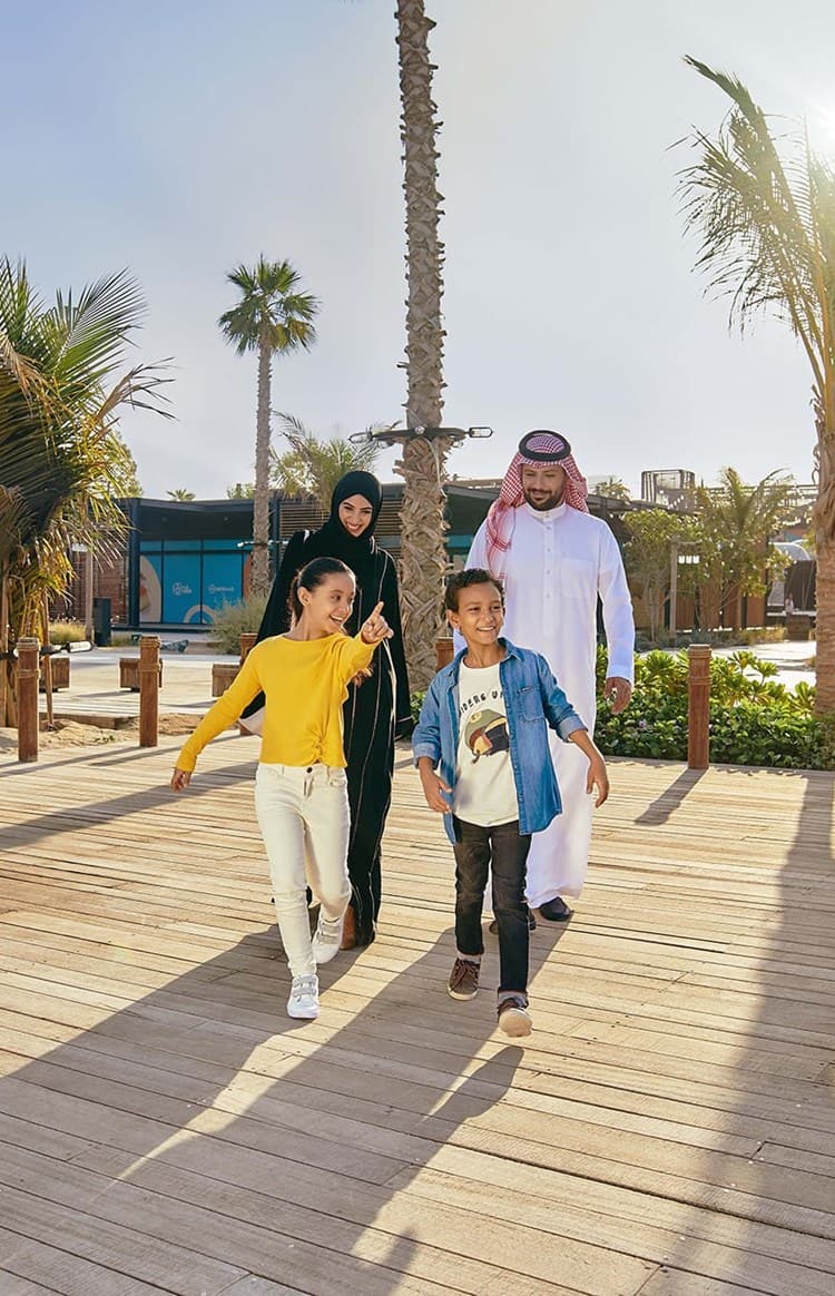 Saudi family with children walking along a wooden seaside boardwalk