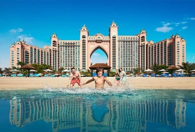 A young family running into the sea with Atlantis, The Palm in the background.