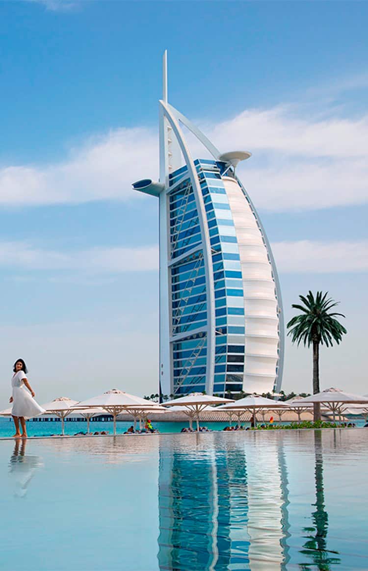 Женщина стоит перед отелем Burj Al Arab в Дубае