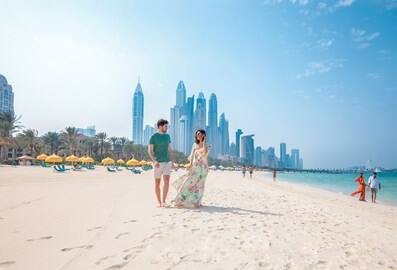 Couple walking on the beach with the Dubai skyline in the background