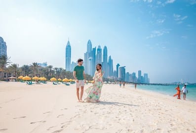 Couple walking on the beach with the Dubai skyline in the background