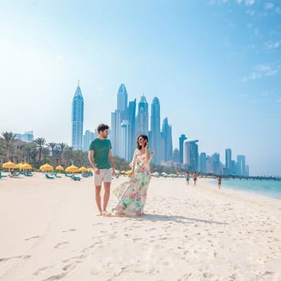 Couple walking on the beach with the Dubai skyline in the background