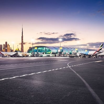 Panoramic view of the outdoor area of Dubai International Airport with parked Emirates planes in front of the building.