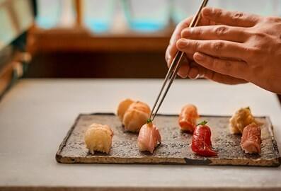 A chef meticulously plating fresh nigiri sushi at Kinoya restaurant