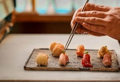 A chef meticulously plating fresh nigiri sushi at Kinoya restaurant