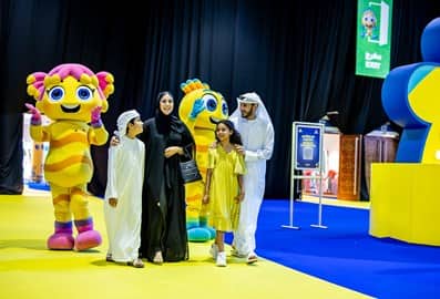 Family posing with a colourful mascot at a summer event