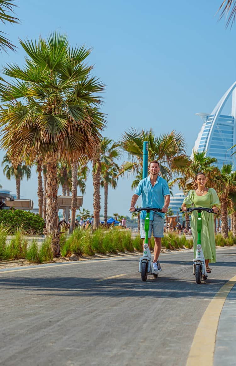 A couple on an e-scooter at Kite Beach.