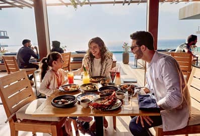 A small family having a relaxed meal at a seaside restaurant.