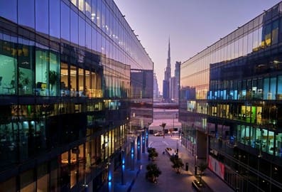 Contemporary buildings lining a pedestrian walkway with Burj Khalifa in the distance